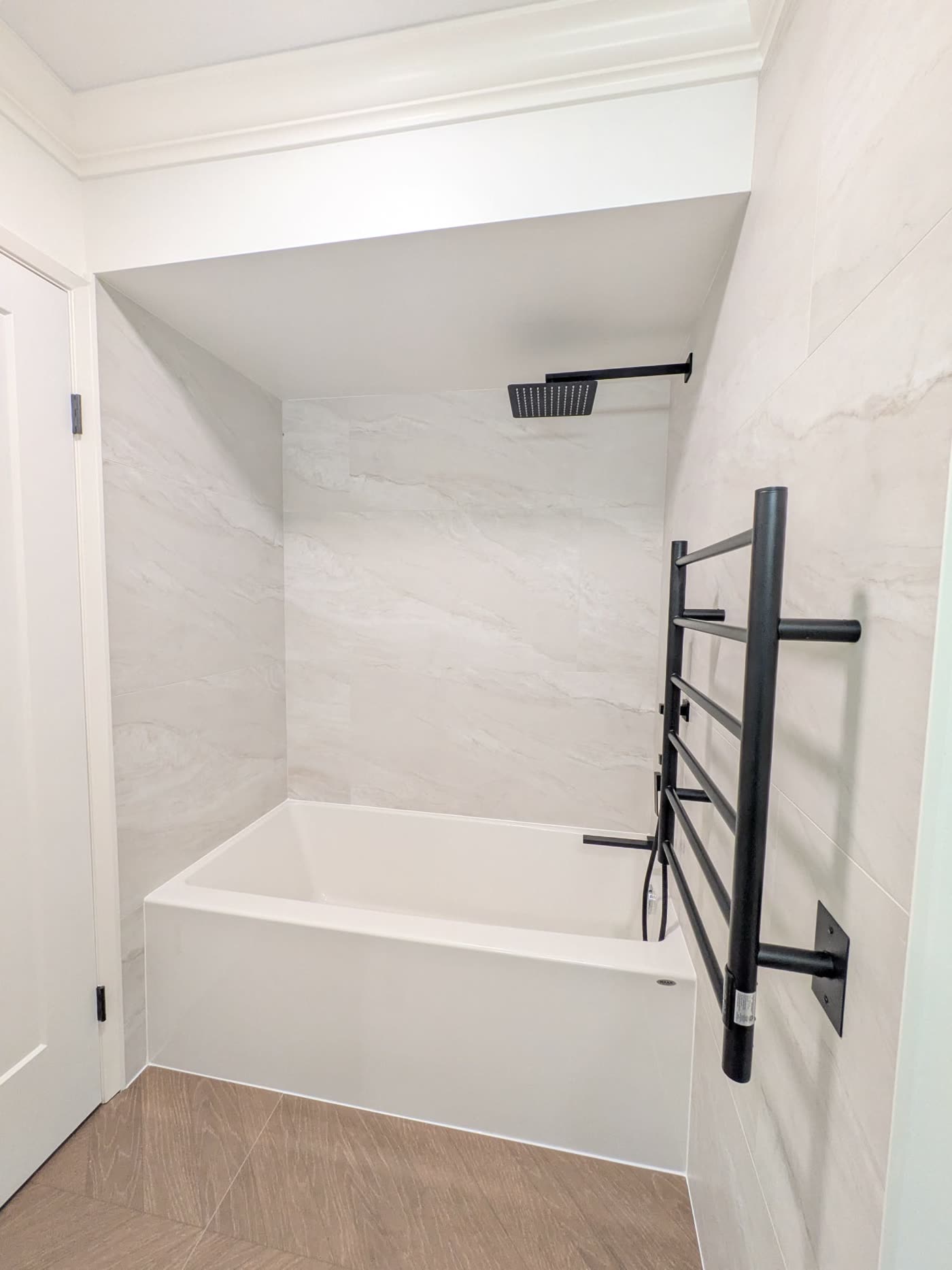 Completed Burnaby bathroom with bathtub marble-look tile and black fixtures