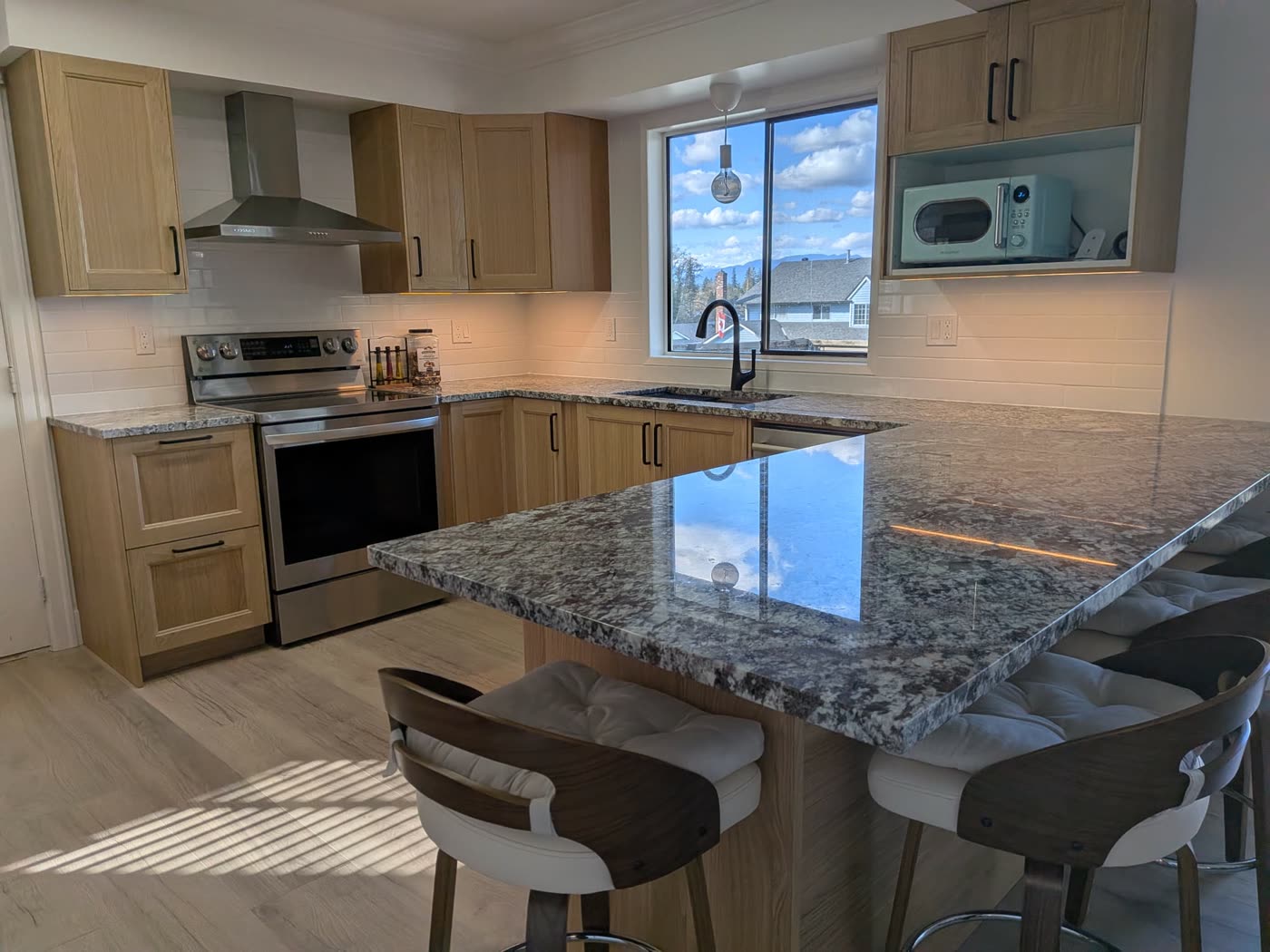 Completed Budova kitchen renovation with wood cabinets and peninsula in Burnaby BC