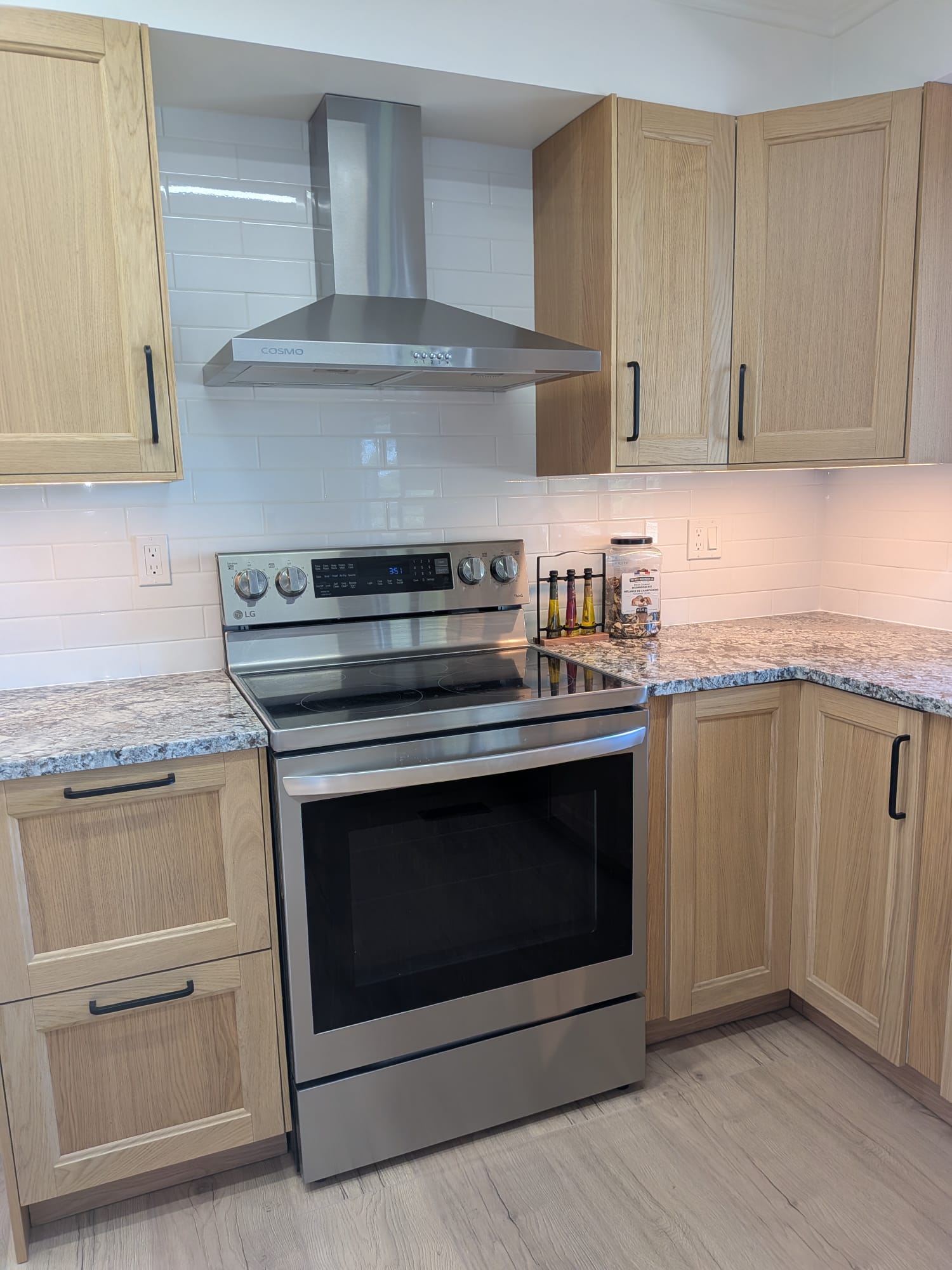 Budova kitchen renovation with natural wood cabinets, range hood and white subway tile backsplash