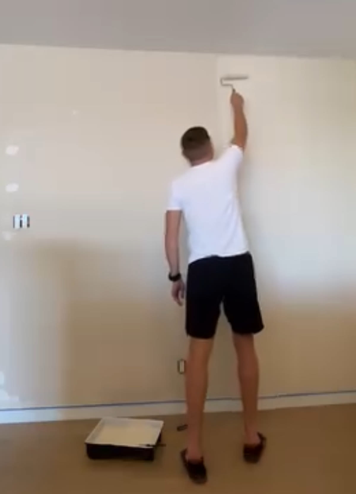 Alex applying interior wall paint with a roller during a Budova painting project