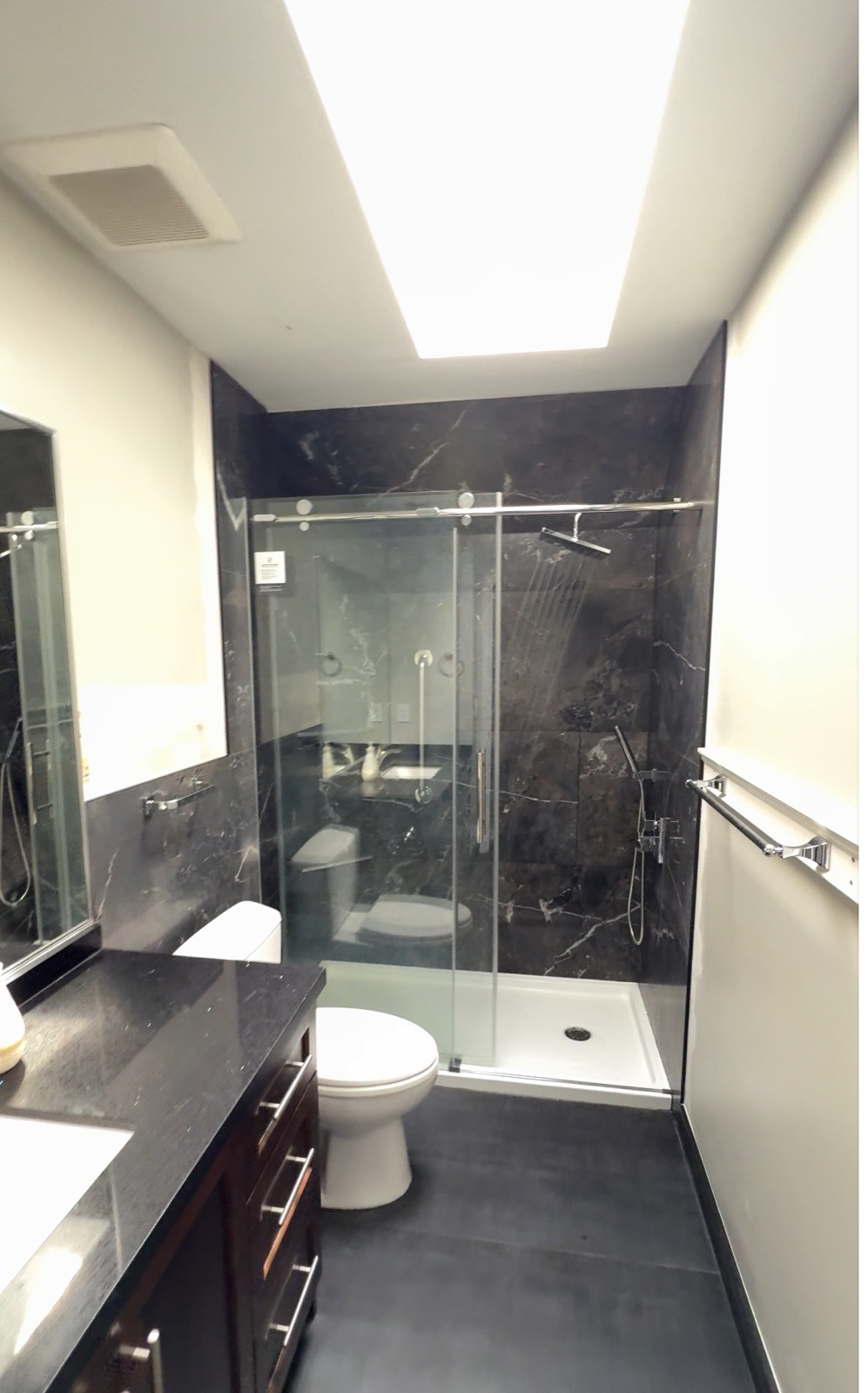 Completed Budova bathroom renovation with glass shower and dark tile in Surrey BC